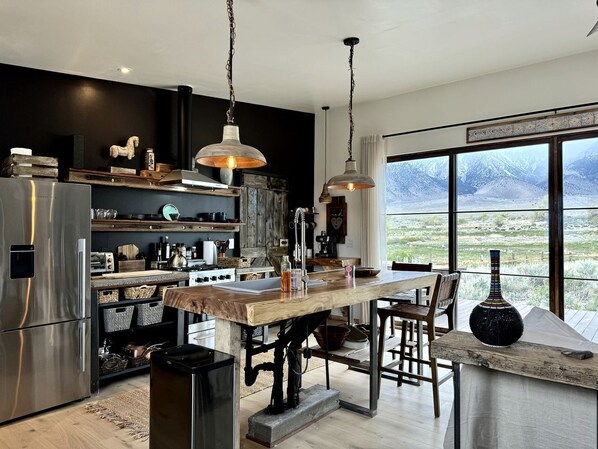A modern kitchen with a wooden island, stainless steel appliances, and a large window offering a mountain view.