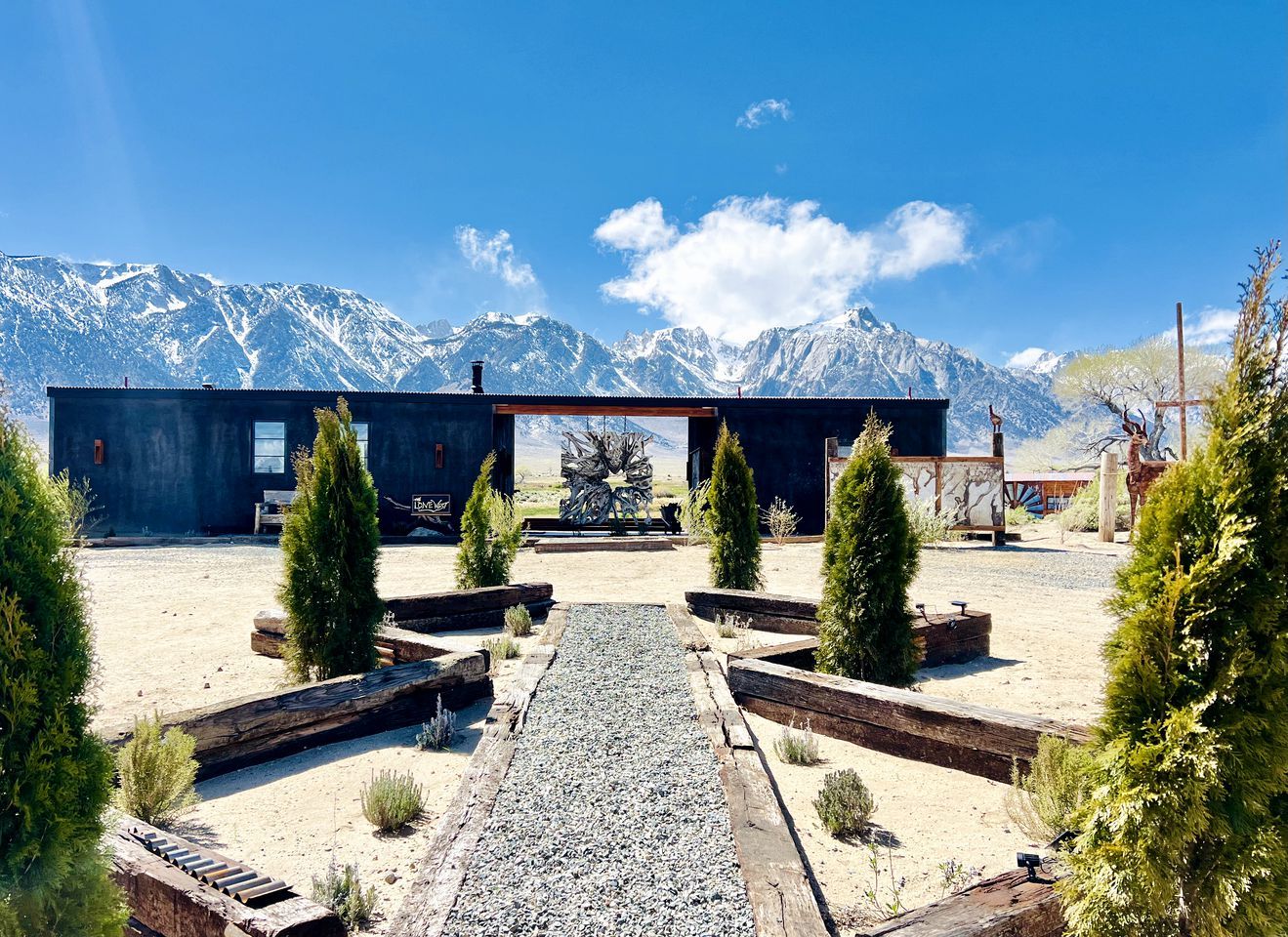 A building with a gravel pathway leading to a mountain view.