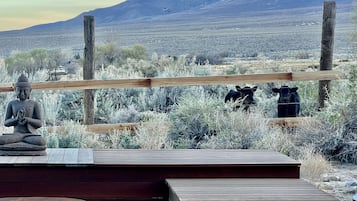 A wooden deck with a statue, a fence, and a mountainous landscape in the background.