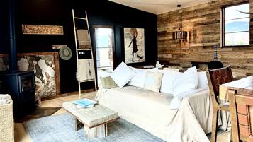 A cozy living room with a sofa, a small table, a fireplace, and a wooden wall.