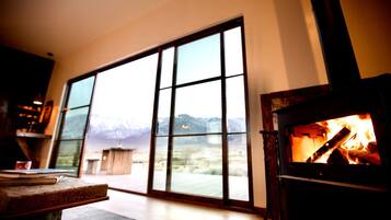 A cozy room with a fireplace, large windows, and a view of mountains.