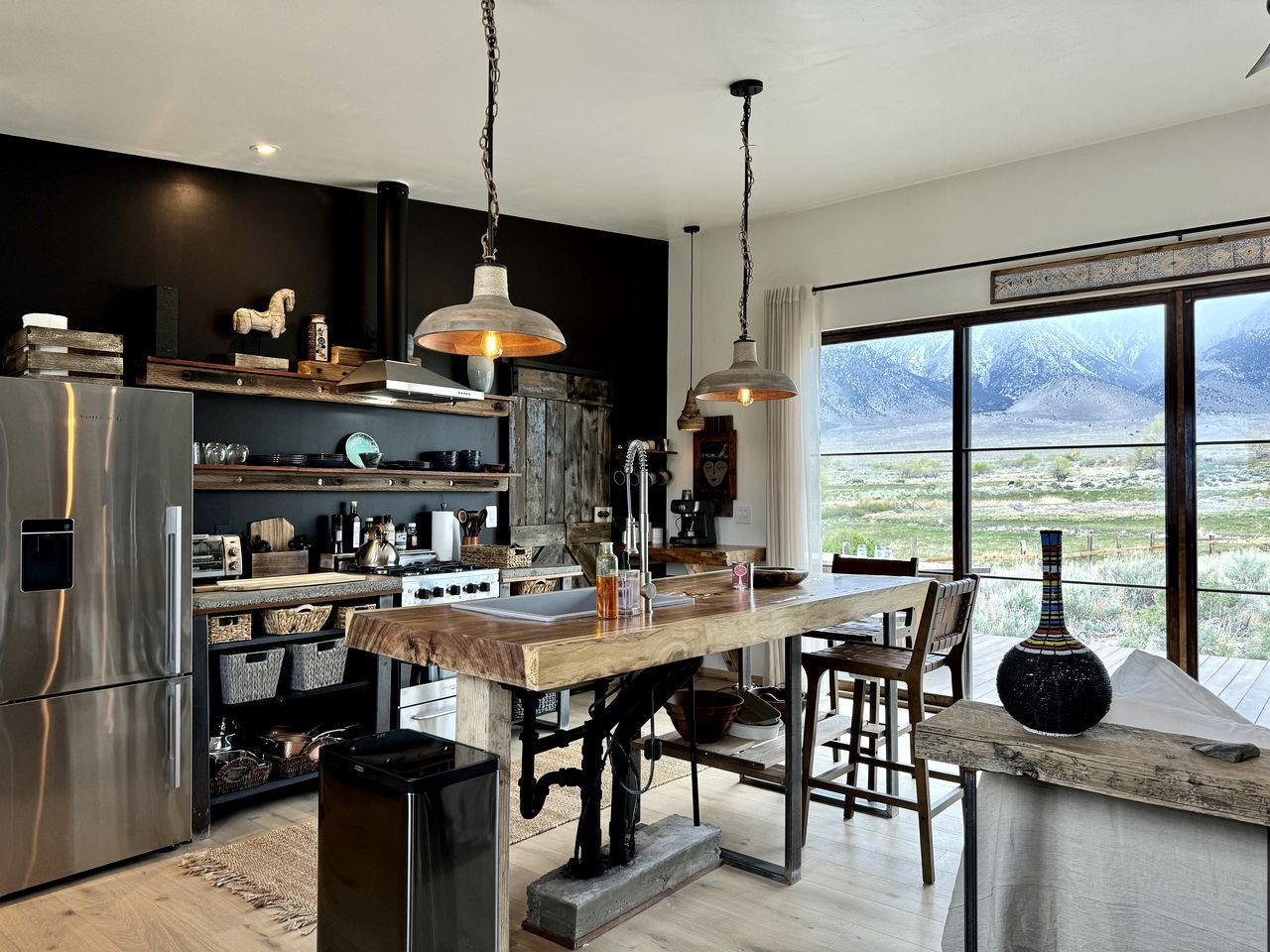 Una cocina moderna con una isla de madera, electrodomésticos de acero inoxidable y un amplio ventanal con vistas a la montaña.
