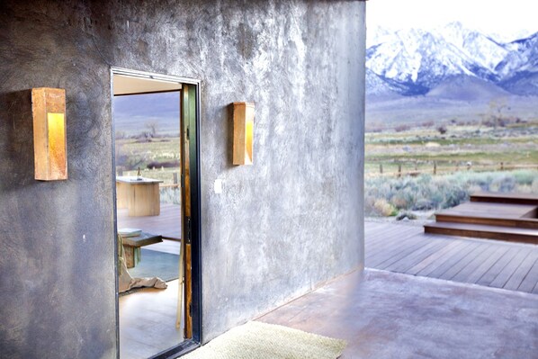 A modern building with a concrete exterior, a wooden deck, and a view of mountains.