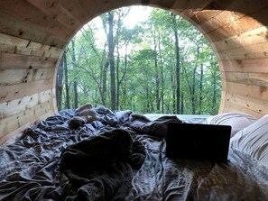 A circular wooden room with a bed, a laptop, and a teddy bear.