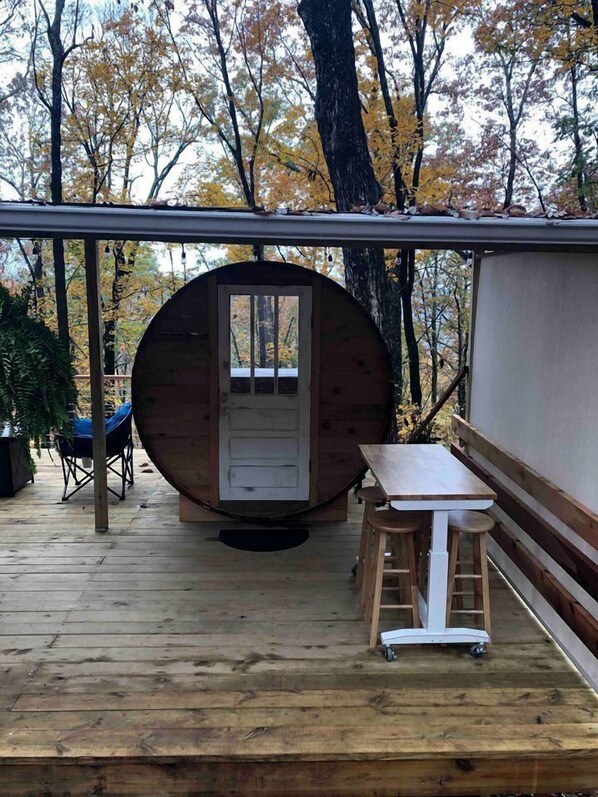 A wooden deck with a circular wooden structure, a table, and a stool.