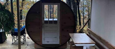 Une terrasse en bois avec une structure circulaire également en bois, une table et un tabouret.