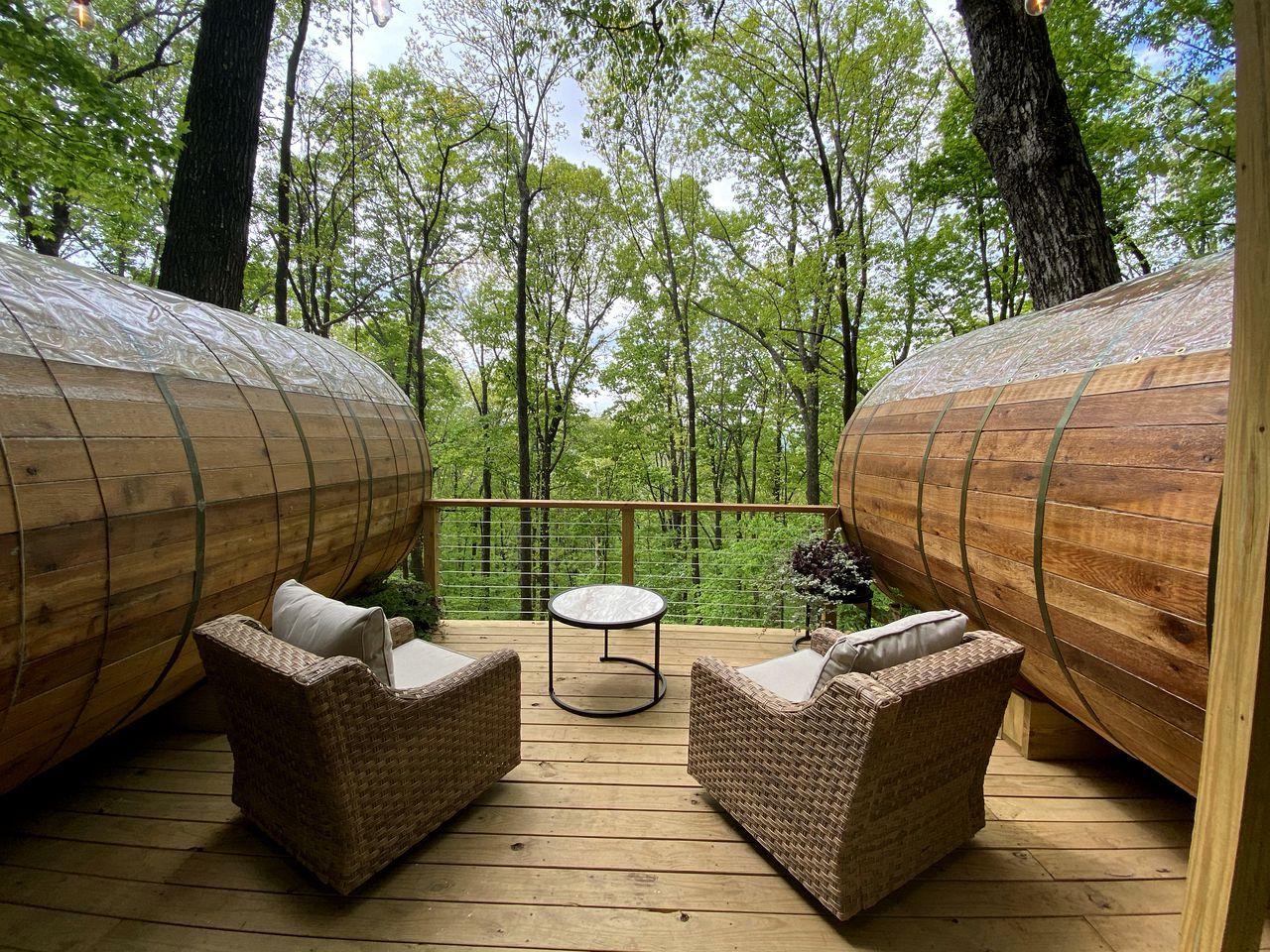 Eine Holzterrasse mit Korbmöbeln und großen, zylindrischen Holzelementen.