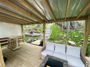 An outdoor deck with a wooden table and chairs, a cushioned bench, and a stone fire pit.