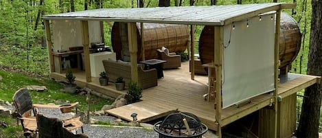 A rustic cabin with a deck, outdoor seating, and a fire pit.