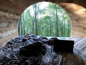A circular wooden room with a bed, a laptop, and a teddy bear. - Canopy Treehouse - Glamp Design with Amazing Views, Wildwood, GA (Wildwood)