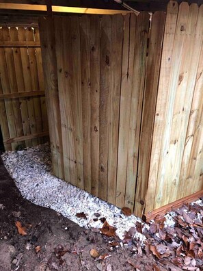Une clôture en bois avec un chemin de gravier menant à une structure également en bois.