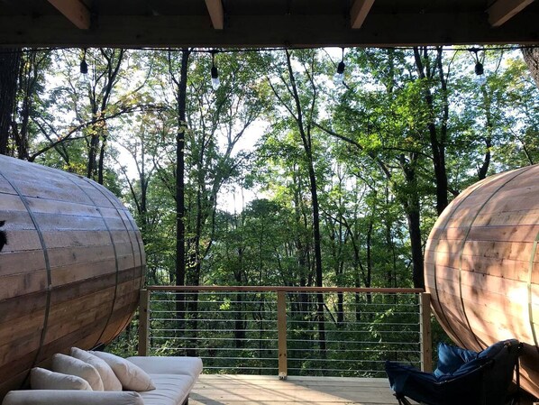 Une pièce en forme de tonneau, faite de bois, avec une rambarde en métal et une vue sur une forêt.