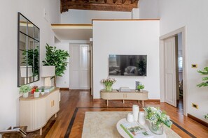 Ein Korridor mit Holzboden, Spiegel, Fernseher und Pflanze.