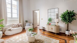 A living room with a sofa, a coffee table, a cabinet, and a large plant. - Charming Nest in the Heart of Lucca: "The Gallo Promenade" Just Steps from the Duomo (Lucca)