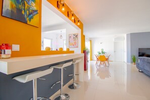 A modern kitchen with a bar area, a dining area with a table and chairs, and a living room with a sofa. - 278 Sesmarias in Carvoeiro (Lagoa)