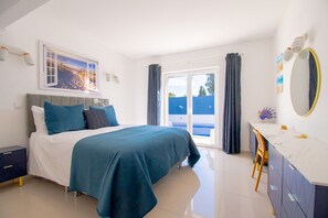 A bedroom with a bed, a desk, a chair, a large window, and a painting on the wall. - 278 Sesmarias in Carvoeiro (Lagoa)