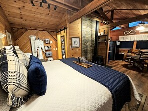 Une pièce chaleureuse avec un lit, un plafond en bois, un mur en pierre et un coin repas.