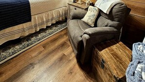 A cozy room with a bed, a chair, a nightstand, and a wooden ceiling. - Romantic Creekside Cabin Retreat with Hot Tub, Fire Pit and Peaceful Forest Views in Sautee Nacoochee, Georgia (Sautee Nacoochee)