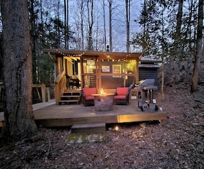 A cabin with a deck, a fire pit, outdoor seating, and a grill. - Romantic Creekside Cabin Retreat with Hot Tub, Fire Pit and Peaceful Forest Views in Sautee Nacoochee, Georgia (Sautee Nacoochee)