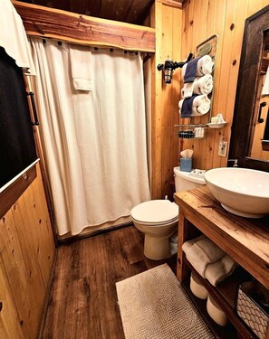 Un baño de madera con inodoro, lavamanos y toallero.