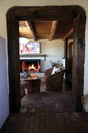 A cozy room with a fireplace, a television mounted above it, and a wicker chair.