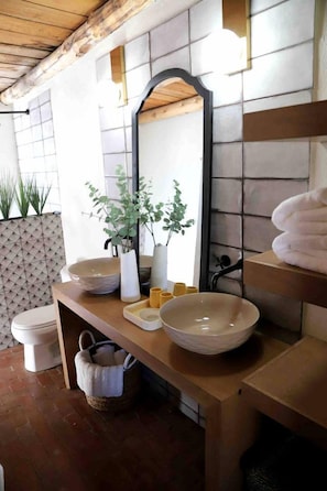 Un baño con tocador de madera, un espejo grande y un lavabo.