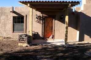 Un edificio rústico con puerta de madera, ventana y porche cubierto.