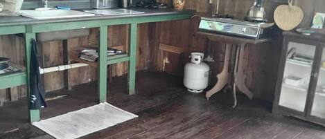 Una cocina rústica con armarios de madera, una estufa a gas y un fregadero.