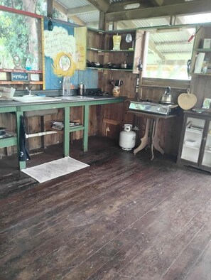 A rustic kitchen with wooden cabinets, a gas stove, and a sink.