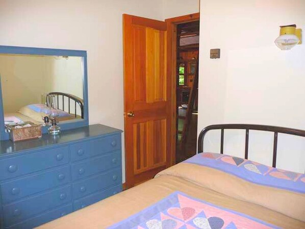 Un dormitorio con cama, cómoda, espejo y puerta.