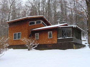 A wooden cabin with a sloped roof, a large window, and a chimney. - Cozy Vacation Cabin near Allegheny State Forest, Pennsylvania (Penfield)