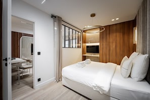 Ein modernes Hotelzimmer mit einem Bett, einem Fernseher, einem Schreibtisch mit Stühlen und einem Spiegel.