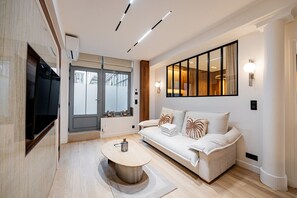 Ein modernes Wohnzimmer mit einer Couch, einem Couchtisch und einem Fernseher.