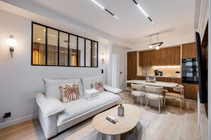 Un saló modern amb un sofà, una taula de centre i una zona de menjador amb cadires.