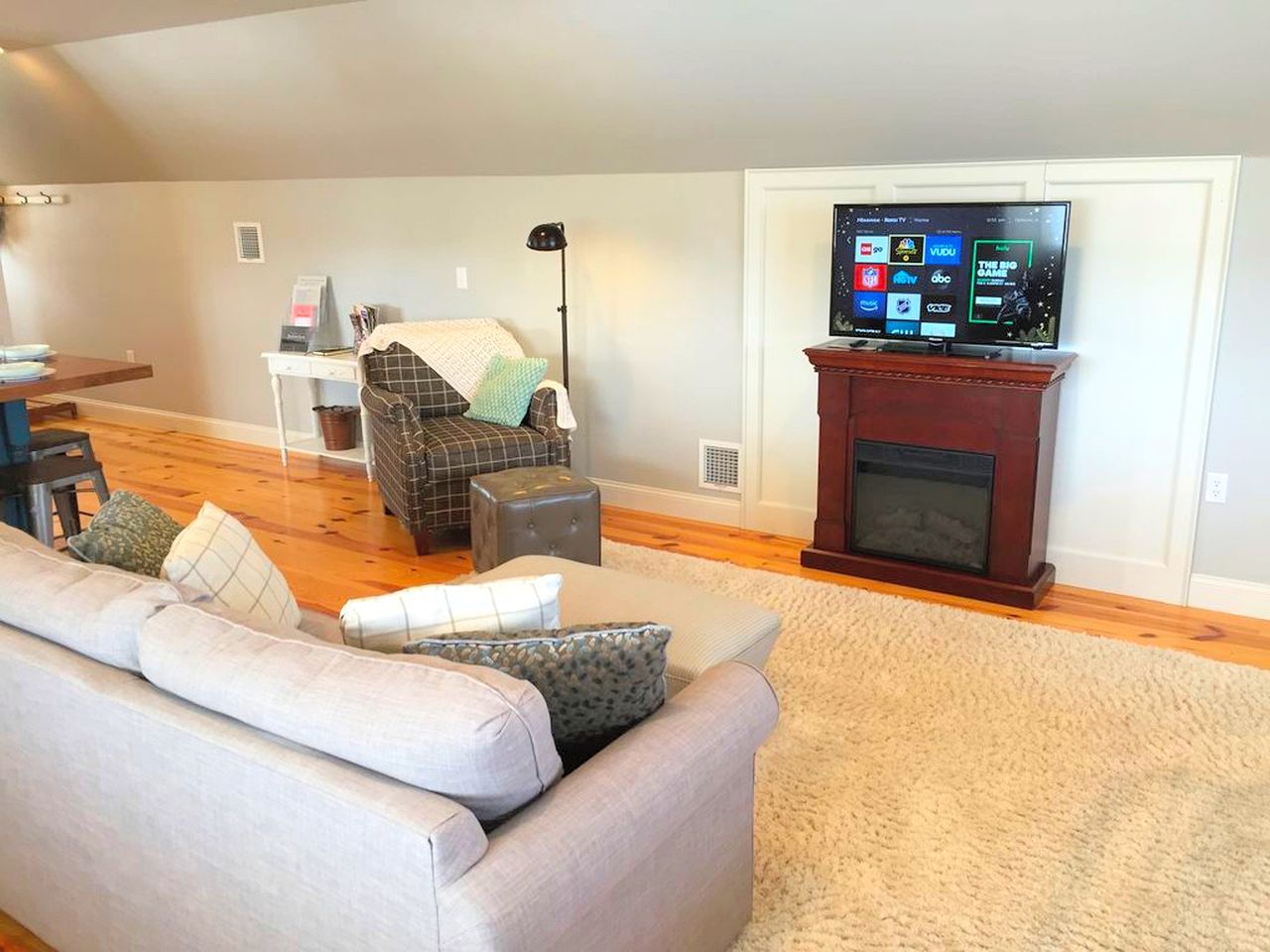 A living room with a sofa, ottoman, and a fireplace.