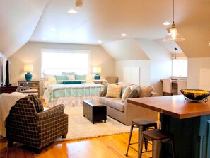 A loft-style bedroom with a large bed, a sofa, a dining area, and a kitchen. - Stylish Cottage Loft Rental on a Farm in Lancaster County near Philadelphia, Pennsylvania (Christiana)
