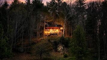 A cabin surrounded by dense forest, with a visible deck and a single-story structure.