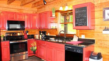 A kitchen with red cabinets, stainless steel appliances, and a chalkboard sign welcoming guests to Red Dog Bar.