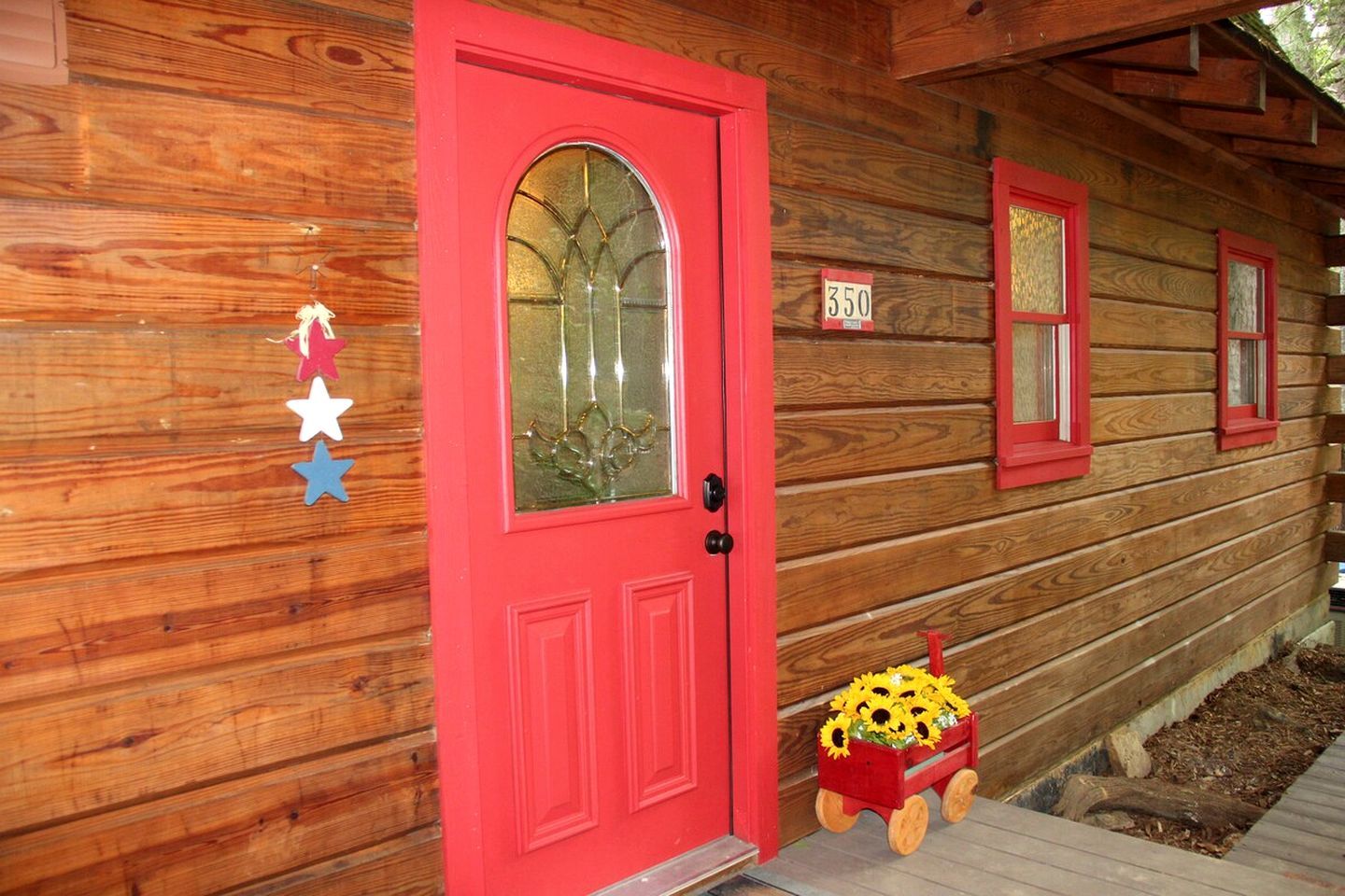 A wooden cabin with a red door, a mailbox, and a number sign.
