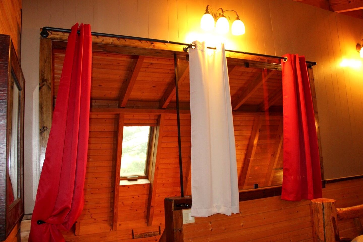A room with wooden walls, a window, and a ceiling with exposed beams.