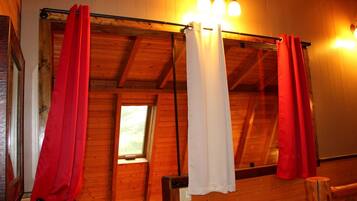 A room with wooden walls, a window, and a ceiling with exposed beams.