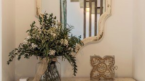 A vintage cabinet with intricate carvings, a vase with flowers, and a decorative mirror.