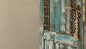 A rustic door with a textured surface and a decorative metal latch.