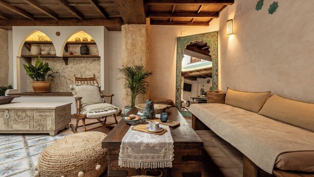A cozy room with a wooden bench, a cushioned bench, a dining table with a placemat, and a potted plant.