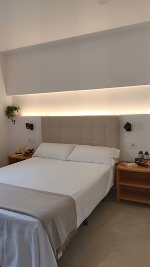 A modern bedroom with a large bed, bedside tables, a wall-mounted light, and a small plant. - Apartment 'Málaga Luz, Beach and City Center' with Sea Views, Wi-Fi and Air Conditioning (Málaga)