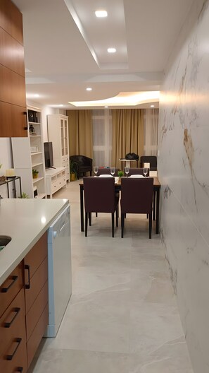 A modern kitchen with a dishwasher, a dining area with a table and chairs, and a living area with a sofa and TV. - Apartment 'Málaga Luz, Beach and City Center' with Sea Views, Wi-Fi and Air Conditioning (Málaga)