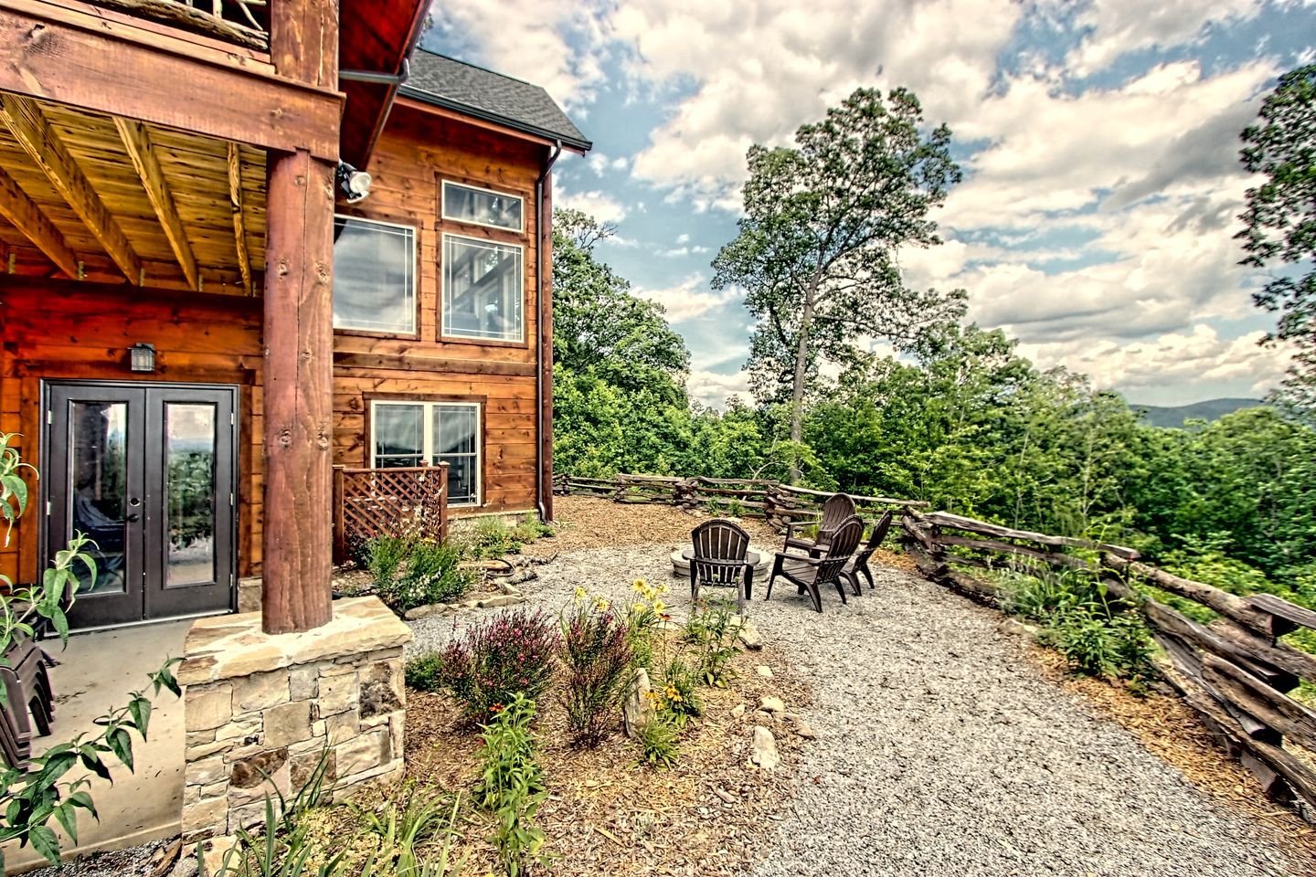 A wooden cabin with a stone foundation, a gravel patio, and a wooden fence.