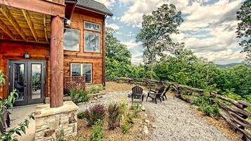 A wooden cabin with a stone foundation, a gravel patio, and a wooden fence.