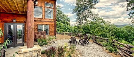 A wooden cabin with a stone foundation, a gravel patio, and a wooden fence.