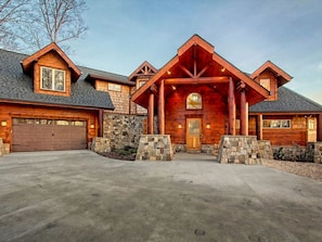 A log cabin with a stone foundation, large garage doors, and a prominent front porch.